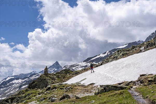 Mountaineer on a rocky hiking trail in a snowfield, Berliner Hoehenweg, mountain landscape with Schrammacher peak, Zillertal Alps, Tyrol, Austria, Europe