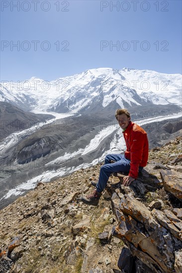 Mountaineer at Traveller's Pass with view of impressive mountain landscape, high mountain landscape with glacier moraines and glacier tongues, glaciated and snow-covered mountain peaks, Lenin Peak and Peak of the XIX Party Congress of the CPSU, Trans Alay Mountains, Pamir Mountains, Osh Province, Kyrgyzstan, Asia