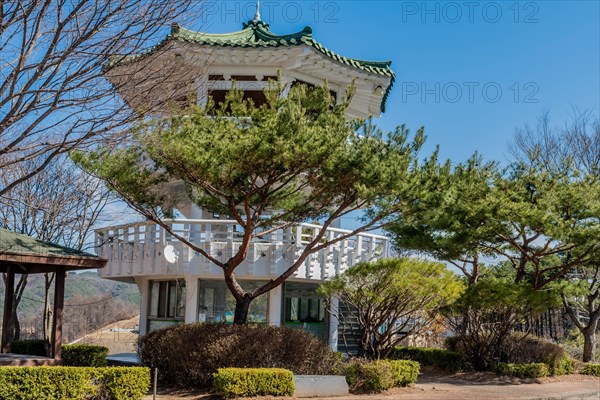 Three story white pagoda under blue sky in roadside park