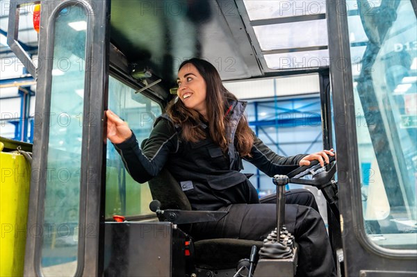 Views trough the window of a woman driving a forklift in a factory