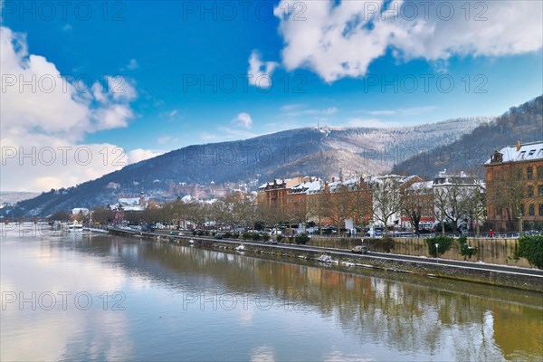Heidelberg, Germany, February 2021: Neckar river with Odenwald forest hill with historical castle. View from Theodor Heuss bridge on sunny winter day with snow, Europe