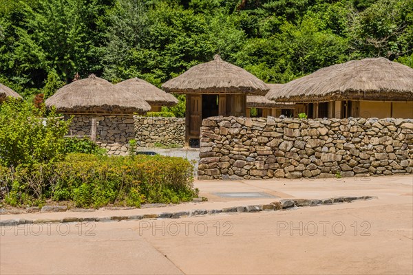 Buyeo, South Korea, July 7, 2018: Traditional Korean village with building built of wood and straw thached roofs behine stone wall in public park at at Neungsa Baekje Temple. For editorial use only, Asia