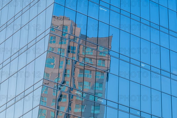 Low angle view of glass office building with reflection of brick building in side windows on sunny day