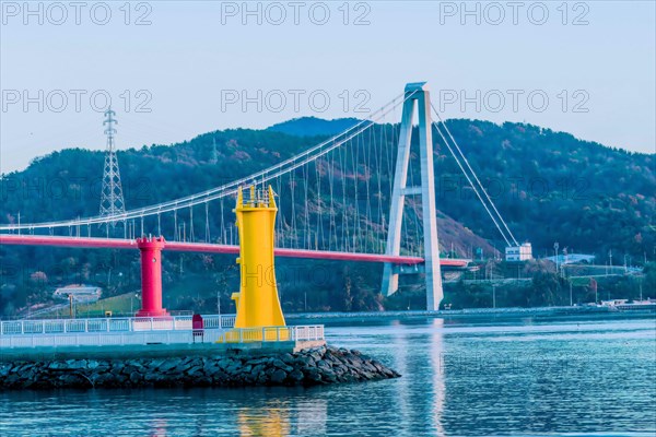 Two lighthouses at fishing port with suspension bridge in background