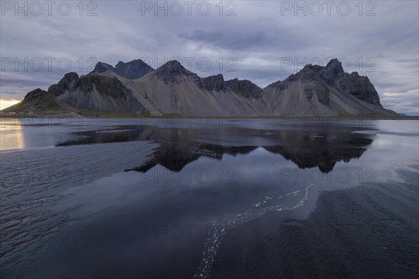 Vestrahorn, mountains with black lava sand, reflection in the water, south coast of Iceland