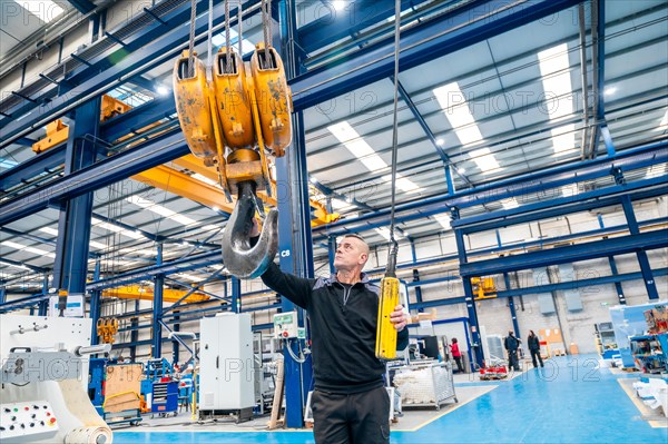 Low angle wide view photo of a male worker using an industrial crane in a logistics factory