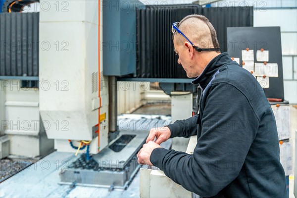 Rear view of an engineer working in a milling cnc machine
