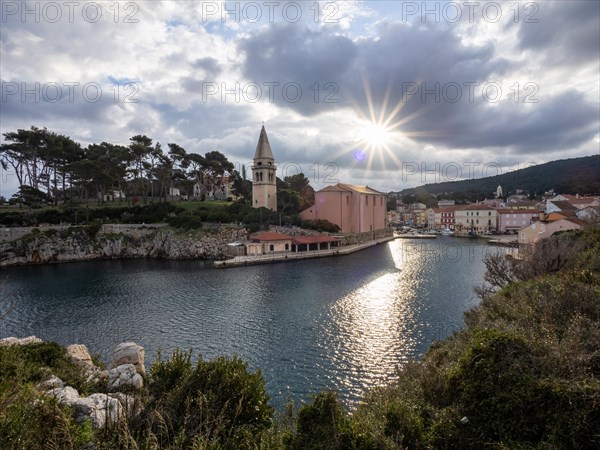 Sun breaking through clouds, view of the harbour entrance of Veli Losinj, with St. Anthony's Church, island of Losinj, Kvarner Gulf Bay, Adriatic Sea, Croatia, Europe