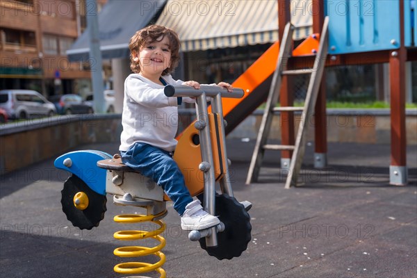 Cute and happy girl looking at camera while playing in a playground with shape of a bike