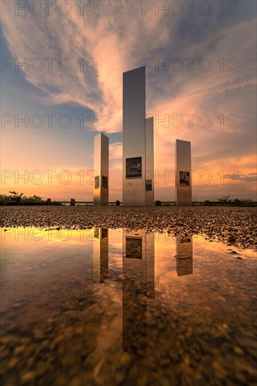 Modern art installation reflected in a puddle of water at sunset, Pforzheim, Germany, Europe