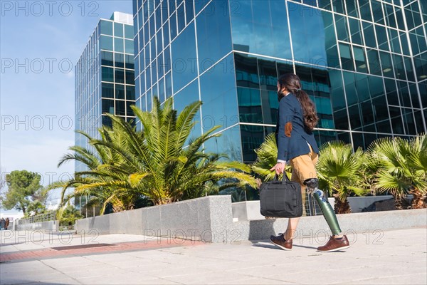 Businessman with prosthetic leg arriving at the office block in a sunny day in the city