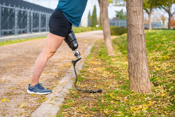 Unrecognizable man with amputee leg using prosthesis stretching after exercising in a park