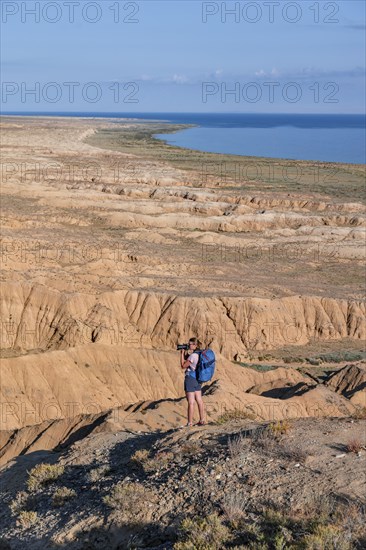 Photographer photographs canyons and eroded hilly landscape, Badlands, Valley of the Forgotten Rivers, near Bokonbayevo, Lake Yssykkoel, Kyrgyzstan, Asia