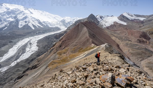 Mountaineer at Traveller's Pass with view of impressive mountain landscape, high mountain landscape with glacier moraines and glacier tongues, glaciated and snow-covered mountain peaks, Lenin Peak, Trans Alay Mountains, Pamir Mountains, Osh Province, Kyrgyzstan, Asia