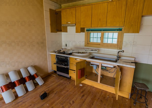 Kitchen area of abandoned house with dirt and electrical fixtures debris on counter top and leaning against wall