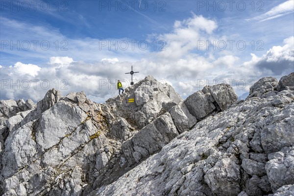 Mountaineer on the rocky summit of the Watzmann Mittelspitze with summit cross, Watzmann crossing, Berchtesgaden National Park, Berchtesgaden Alps, Bavaria, Germany, Europe