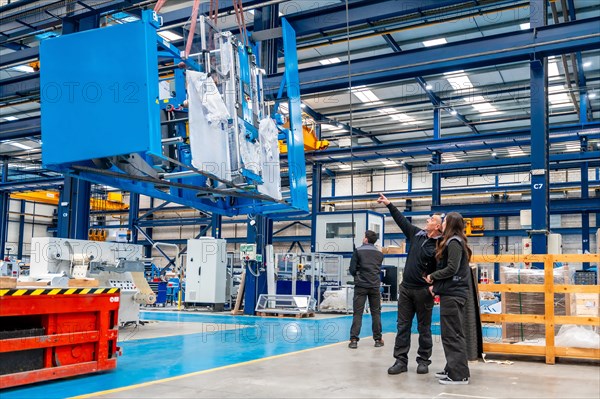 Team of engineers lifting heavy machinery using a crane inside a cnc modern logistic factory