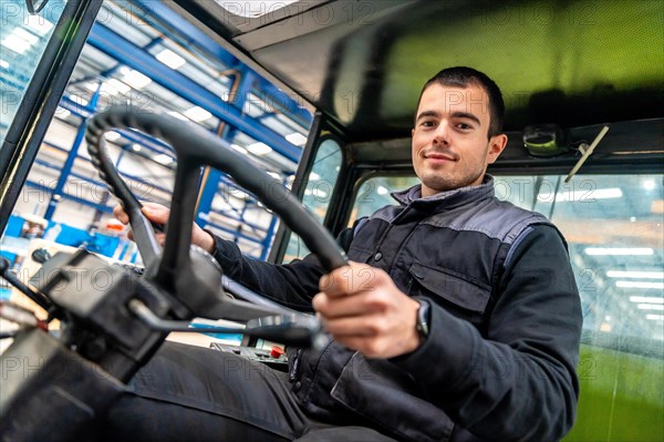 Male woker driving a forklift in a modern cnc logistic factory