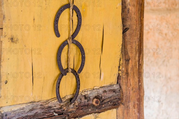 Three rusty horseshoes hanging on wooden wall