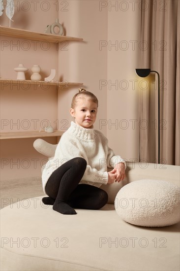 Calm five years old girl sits on couch