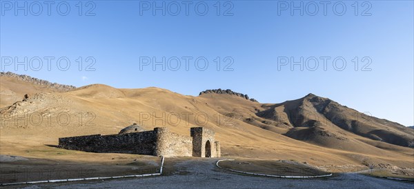 Historic caravanserai Tash Rabat from the 15th century, in the evening light with golden hills, Naryn region, Kyrgyzstan, Asia