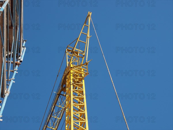 Yellow tower crane and scaffolding over blue sky