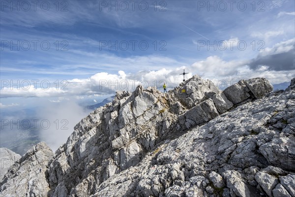 Mountaineer on the rocky summit of the Watzmann Mittelspitze with summit cross, Watzmann crossing, Berchtesgaden National Park, Berchtesgaden Alps, Bavaria, Germany, Europe