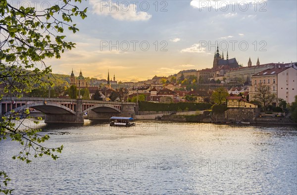 Boats on Vltava river and Hradcany castle in the background, in Prague, Czech Republic (Czechia), at sunset