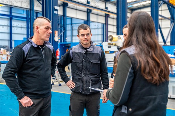 Team of workers and engineers talking standing in a factory