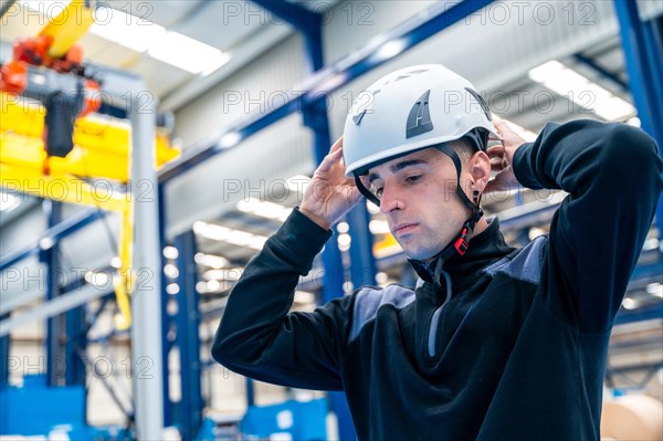 Close-up side view of a worker adjusting helmet in a logistic center