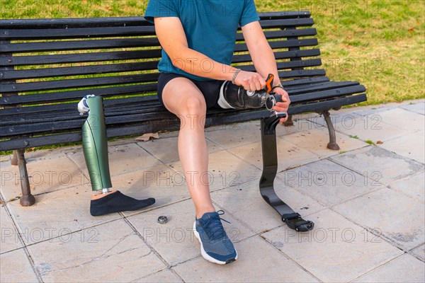 Sportsman adjusting the screws on an artificial prosthetic leg sitting on a bench before running