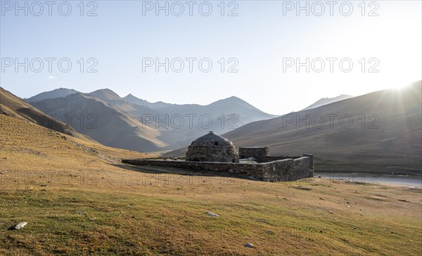 Historic caravanserai Tash Rabat from the 15th century, in the evening light with golden hills, Naryn region, Kyrgyzstan, Asia