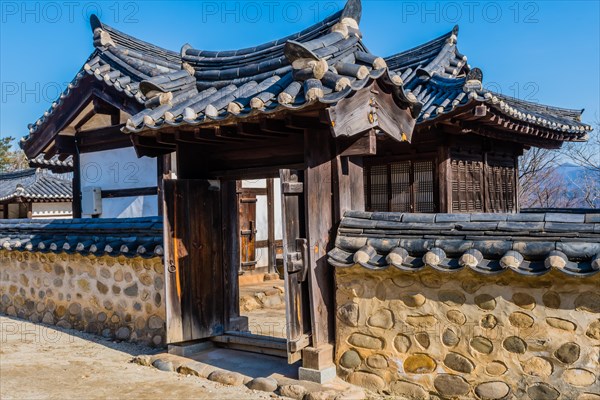 Traditional gate with ceramic tile roof set in mud stone wall at display of Korean architecture in public park