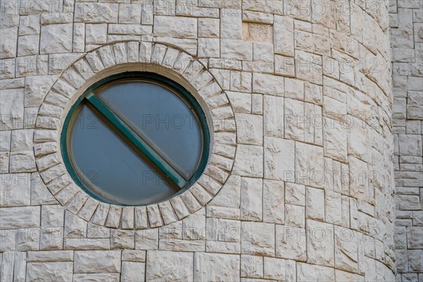 Exterior view of round window in white brick facade