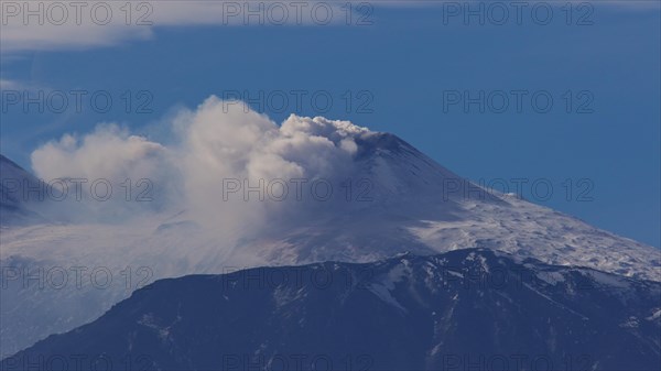 Mount Etna. Smoke rises from a snow-covered volcano under a clear blue sky, Etna, Taormina, Eastern Sicily, Sicily, Italy, Europe