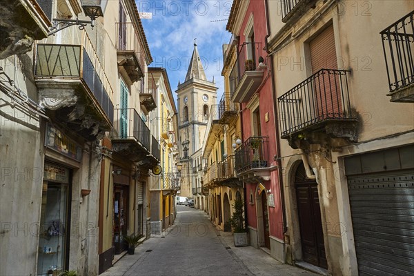 A narrow alley with colourful houses and a church tower at the end, Novara di Sicilia, Sicily, Italy, Europe