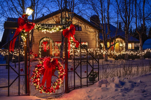 Bed and breakfast with kitschy Christmas decorations at dusk, snow, Alaska Highway, Alaska