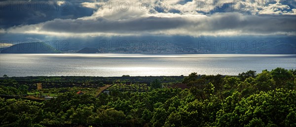 View of the island of Faial and the town of Horta with sun rays breaking through the clouds, Horta, Faial, Azores, Portugal, Europe