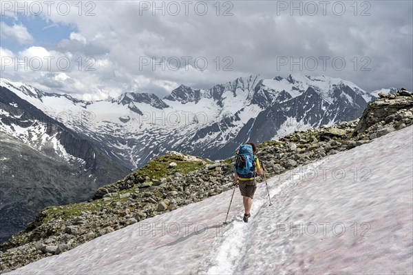 Mountaineer on hiking trail with snow, Berliner Hoehenweg, mountain landscape with glaciated peaks Hochfeiler and Hoher Weisszint, Zillertal Alps, Tyrol, Austria, Europe