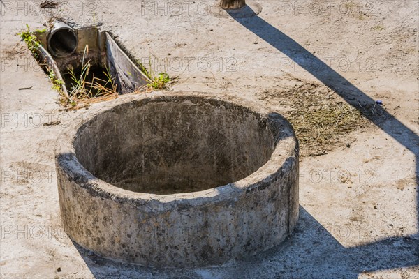 Closeup of concrete irrigation well and drainage pipe used for irrigation of crops in rural community