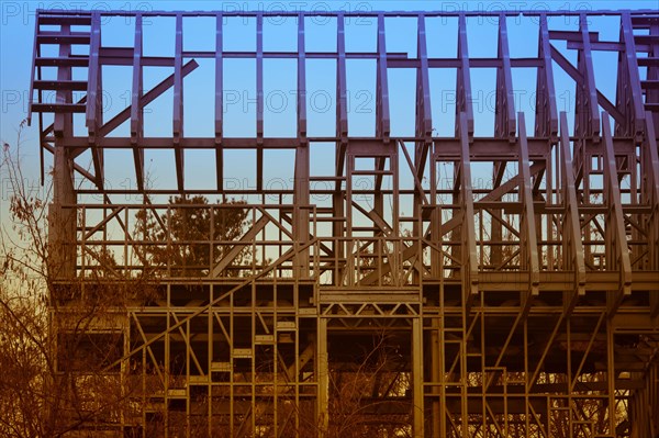 Closeup of metal frame of unfinished building abandoned in wooded countryside on an overcast day