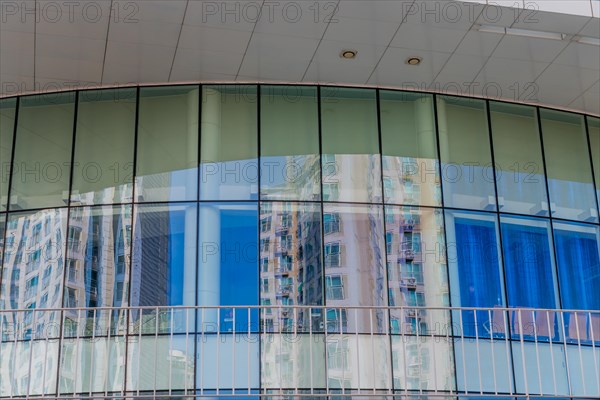 Low angle view of brick and glass office building with reflections of surrounding buildings in window on sunny day