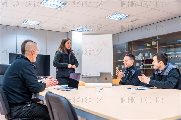 Coworkers supporting and applauding an idea during a meeting in a factory