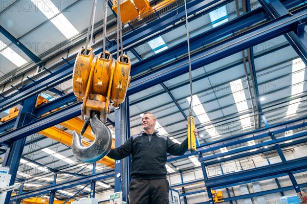 Operator controlling a industrial crane with remote control in a logistics factory