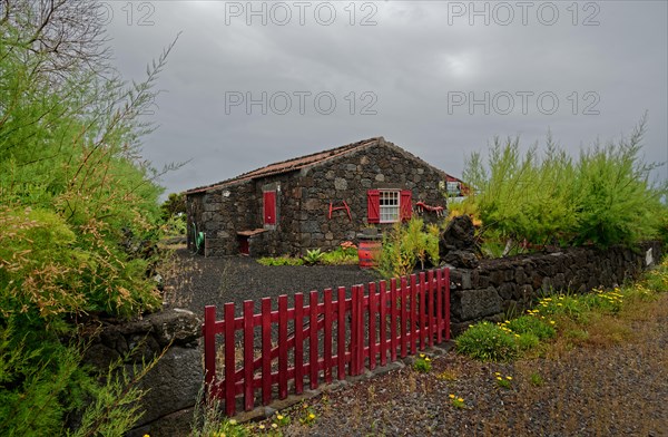 Stone house with red shutters and door and a red fence in a rural area, North Coast, Santa Luzia, Pico, Azores, Portugal, Europe