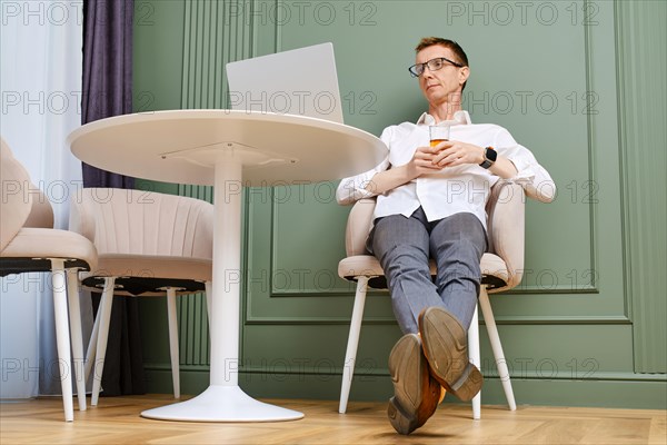 Middle aged man relaxing in front of laptop at home