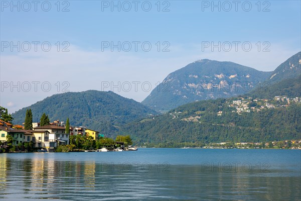 Waterfront in City of Riva San Vitale with Mountain View on Lake Lugano in a Sunny Summer Day in Riva San Vitale, Ticino, Switzerland, Europe