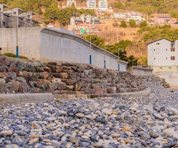 Landscape of Pebble Beach, South Korea with unfinished new construction in the left frame and white buildings on the side of a hill in the background