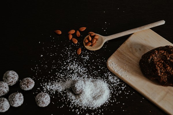 Homemade cookies with almonds and coconut shavings on a dark surface