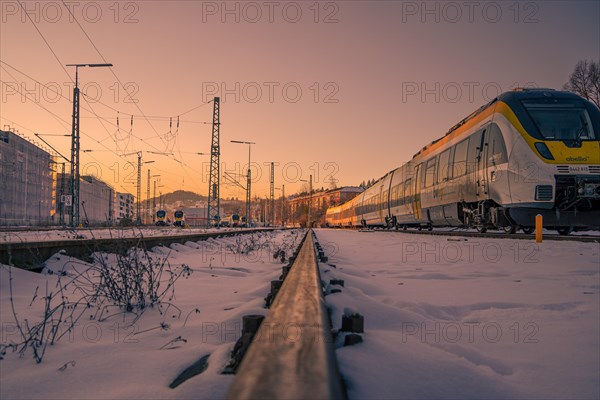 Train on snow-covered tracks at sunset with focus on foreground, Pforzheim, Germany, Europe